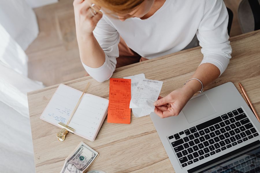 Woman sorting receipts while planning her budget on a laptop